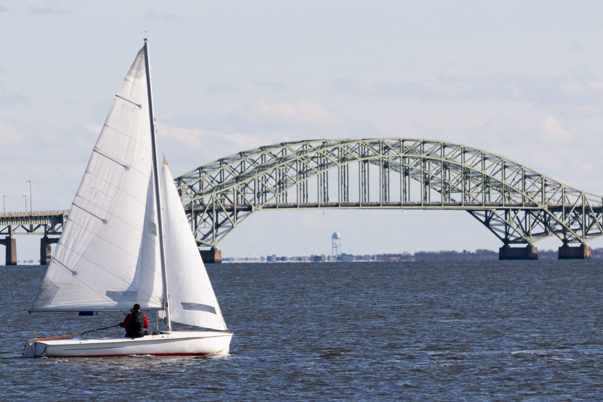 Small sailboat sailing past the great south bay bridge